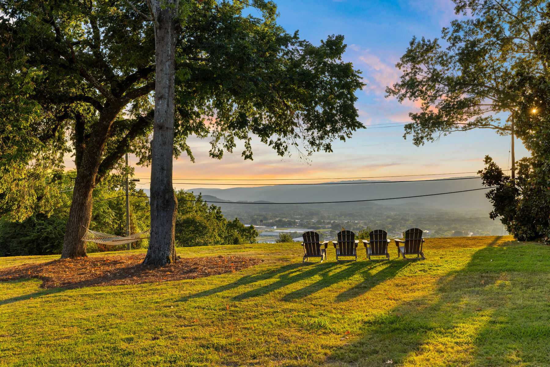 Adirondack chairs beneath trees overlooking Chattanooga