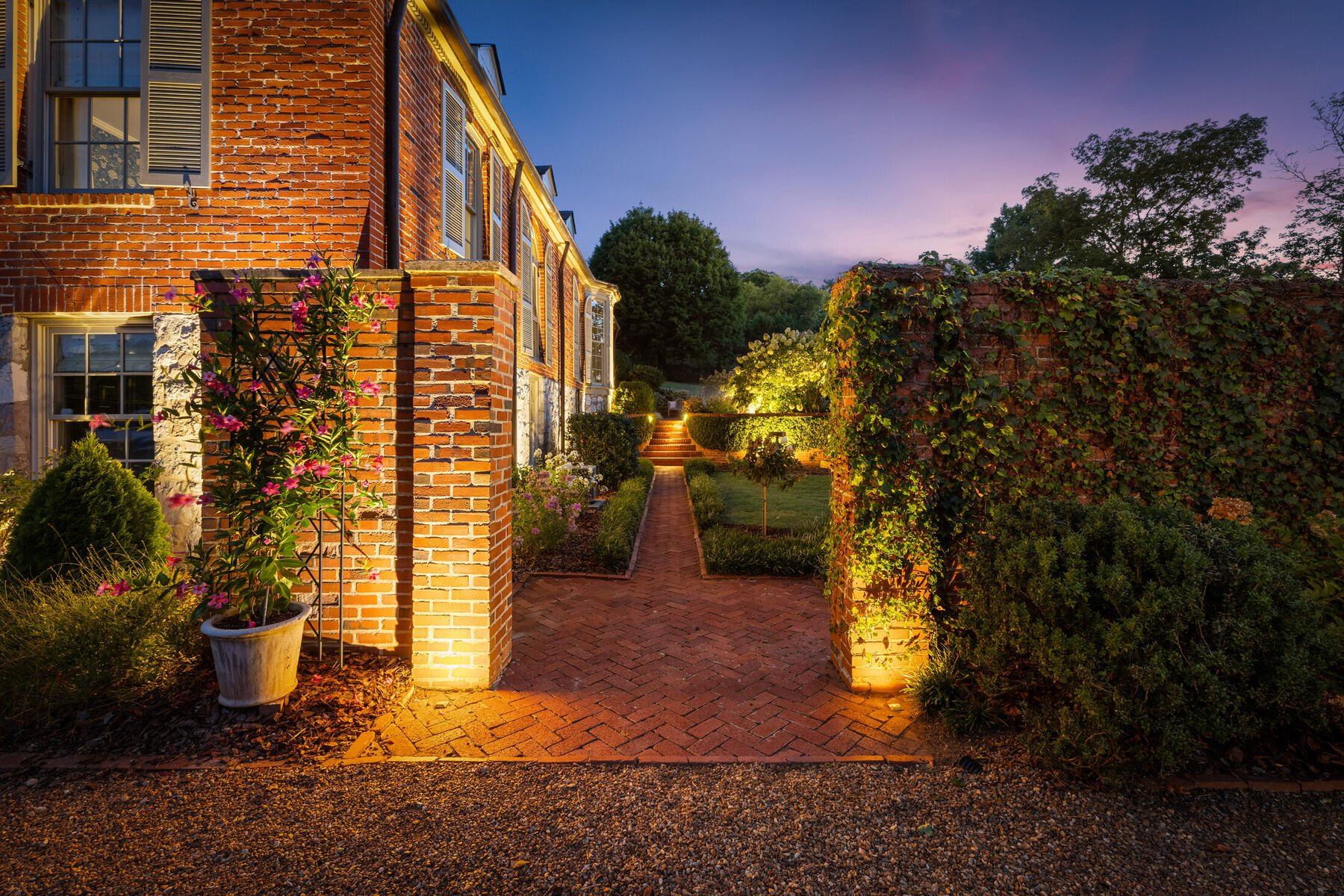 Illuminated brick path beside Oak Cliff Manor at night