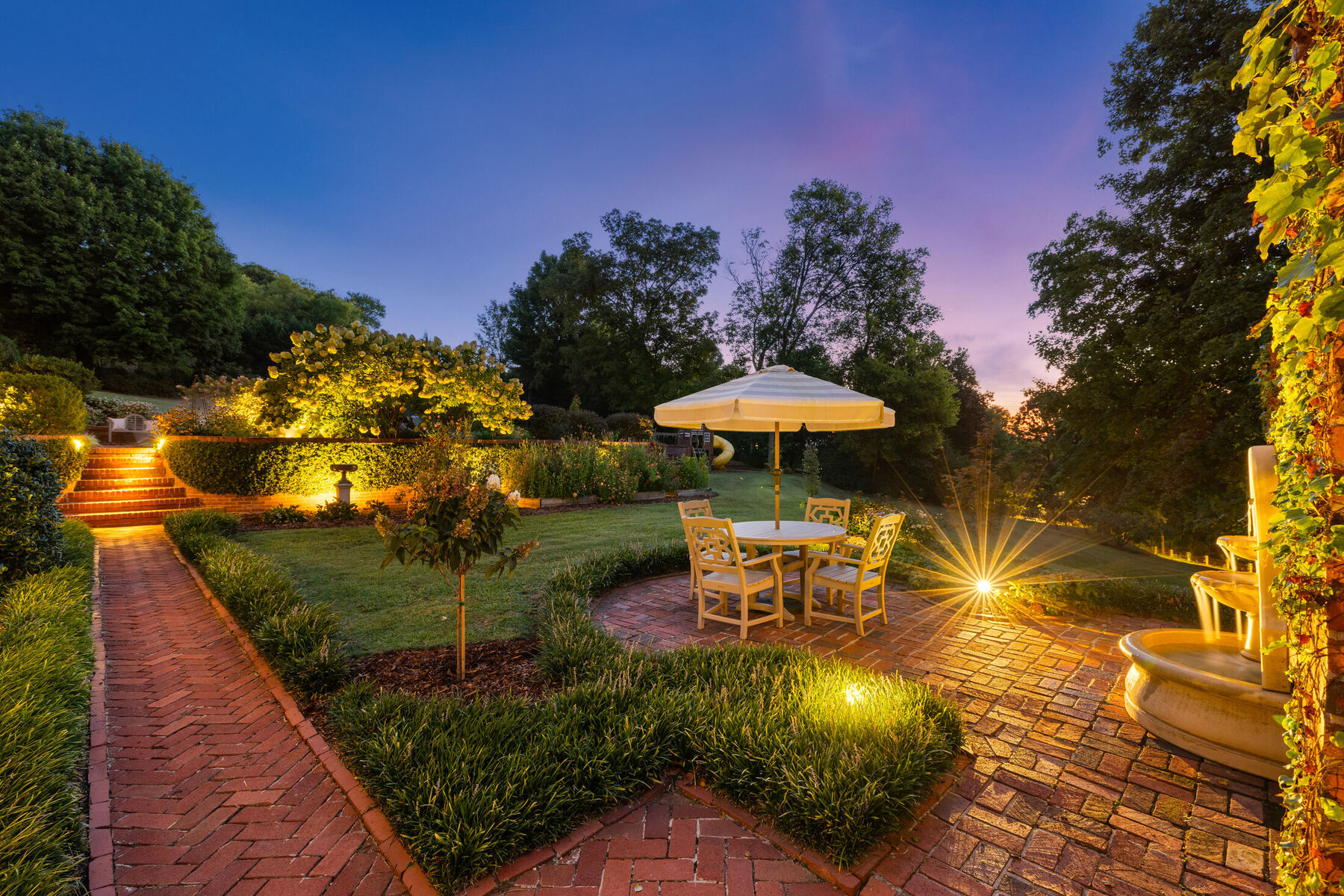 Illuminated garden path and fountain at twilight